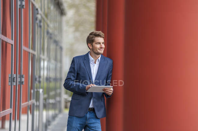 Joven hombre de negocios usando tableta fuera de un edificio - foto de stock