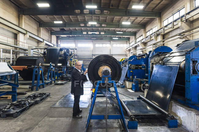 Старший бизнесмен рассматривает продукцию на резиноперерабатывающем заводе — стоковое фото