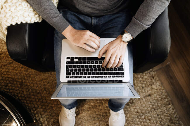 Hombre sentado en casa, usando laptop, primer plano - foto de stock