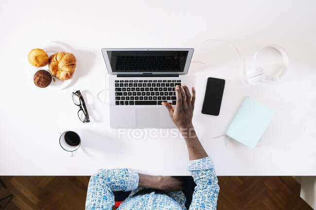 Homme utilisant un ordinateur portable tout en travaillant au bureau à la maison — Photo de stock
