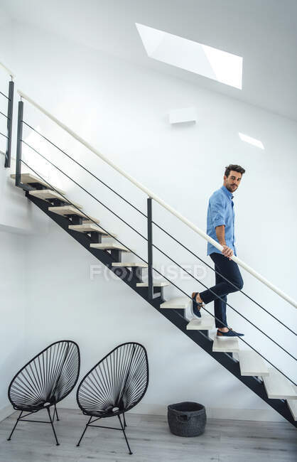 Metà uomo adulto che scende le scale galleggianti in attico moderno — Foto stock