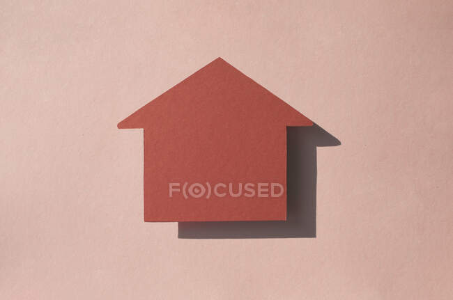 Estudio plano de papel en forma de casa cortado sobre fondo rosa pastel - foto de stock