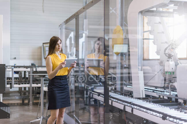 Confident female professional holding digital tablet examining production in factory — Stock Photo