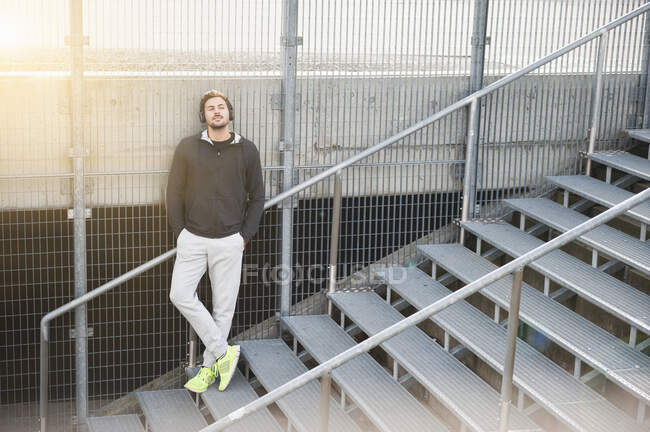 Joven deportivo escuchando música en las escaleras - foto de stock