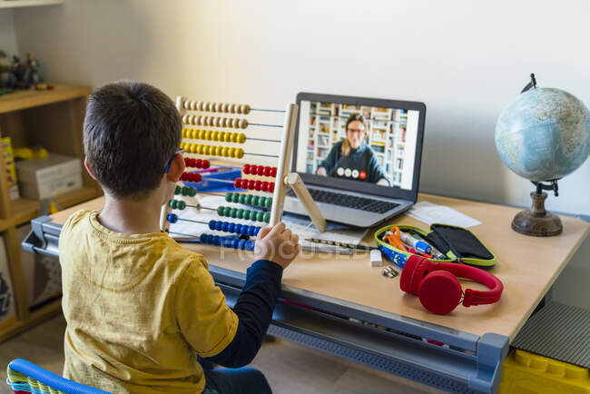 Menino usando ábaco com professor em chamada de vídeo durante a escola em casa — Fotografia de Stock