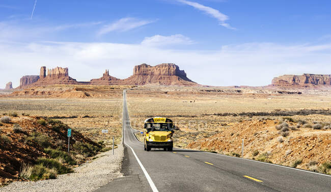 School bus on desert road at Monument Valley Tribal Park against sky, Utah, USA — Stock Photo