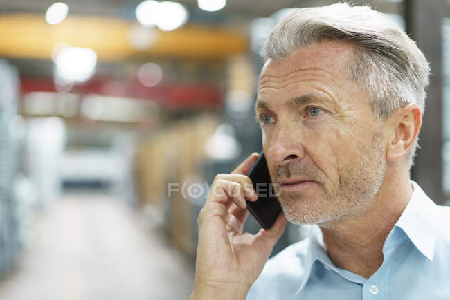 Портрет взрослого бизнесмена по телефону на заводе — стоковое фото