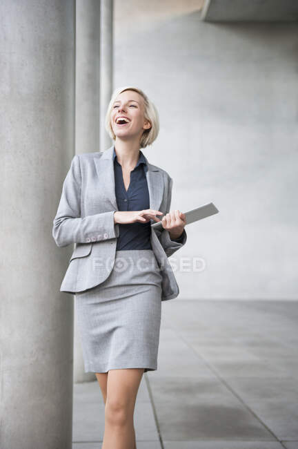 Portrait of laughing blond businesswoman with tablet — Stock Photo
