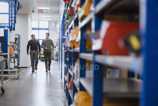Двое мужчин ходят и разговаривают на фабрике — стоковое фото