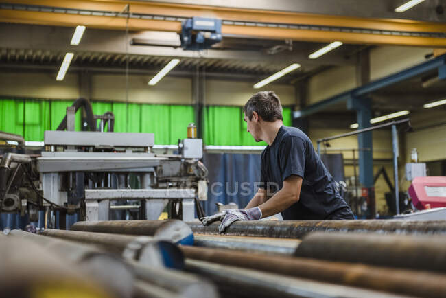 Mann arbeitet mit Metallstangen in einer Fabrik — Stockfoto