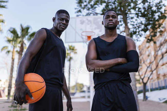 Young men with basketball on basketball court — Stock Photo