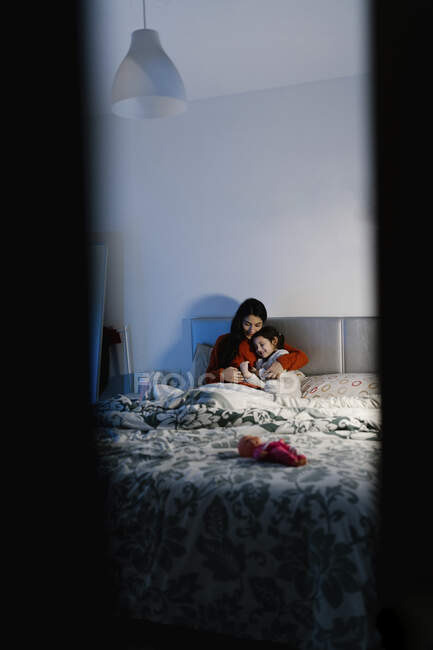 Mãe e sua filhinha abraçando juntos na cama — Fotografia de Stock