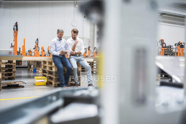 Двое мужчин делят стол на фабричном цехе — стоковое фото