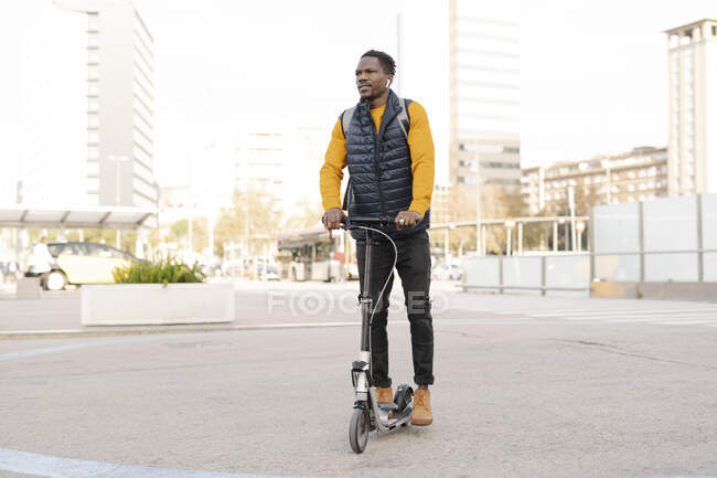 Giovane uomo cavalcando e-scooter in città — Foto stock