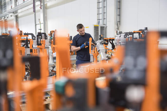 Hombre trabajando en una máquina en una fábrica - foto de stock