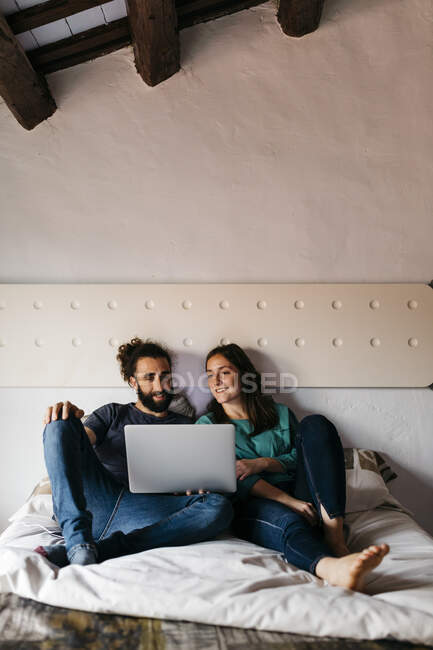 Casal assistindo filme sentado na cama em casa — Fotografia de Stock