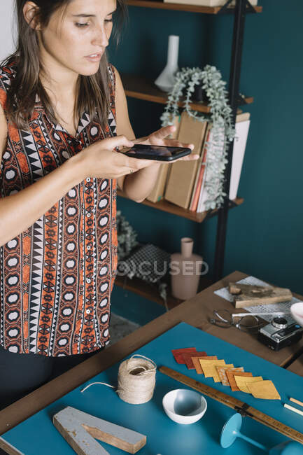 Jeune femme créative prenant photo smartphone de la décoration sur la table — Photo de stock
