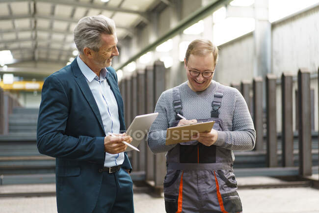 Счастливый бизнесмен с планшетом и работник с планшетом на заводе — стоковое фото