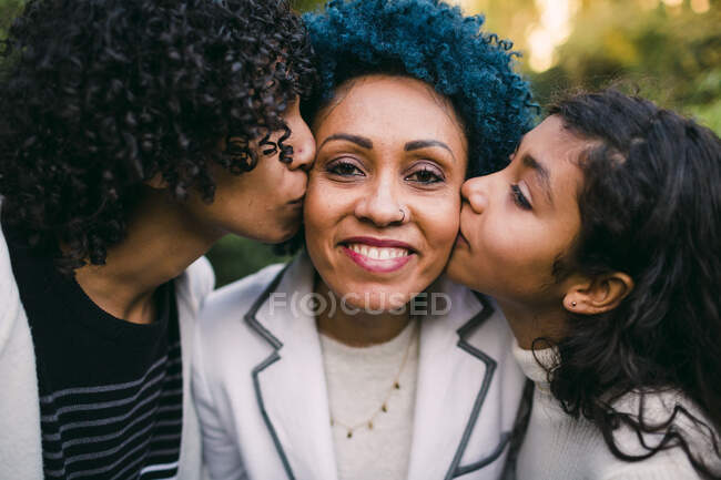 Primo piano di bambini amorevoli che si baciano sulle guance della madre nel parco — Foto stock