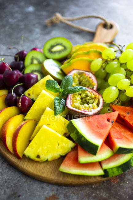 Salade de fruits avec pastèque, kiwi, fruit de la passion, raisin, cerise, pêche et melon sur planche à découper — Photo de stock