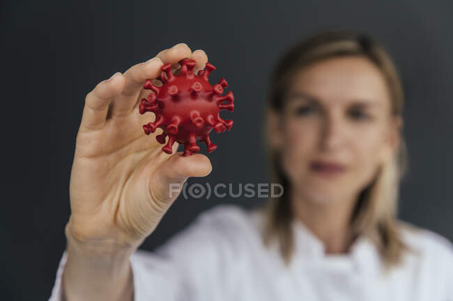 Main d'une scientifique détenant un modèle 3D du virus CoV-2 du SRAS, gros plan — Photo de stock