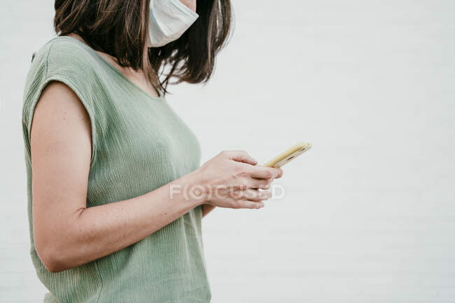 Женщина в защитной маске с помощью мобильного телефона — стоковое фото