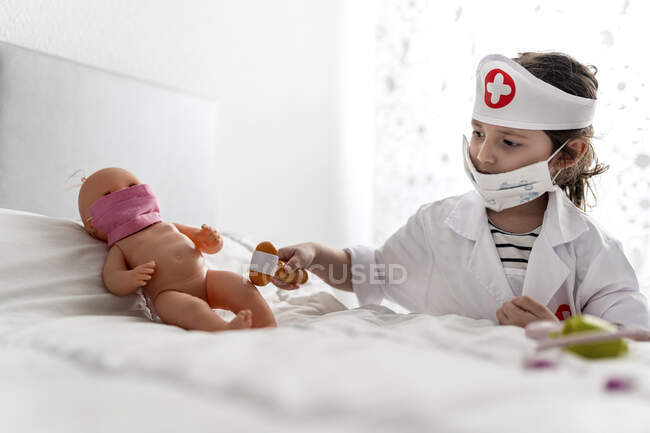 Ragazza in costume del medico prendersi cura della sua bambola con una maschera — Foto stock