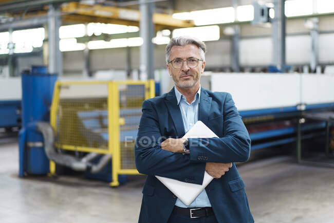 Портрет уверенного взрослого бизнесмена, держащего ноутбук на заводе — стоковое фото
