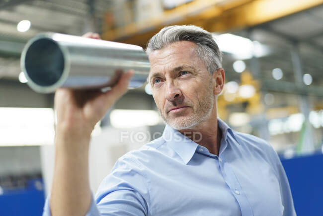 Empresario sosteniendo tubería de acero en una fábrica - foto de stock