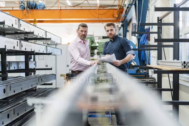 Two men examining piece of metal in a factory — Stock Photo