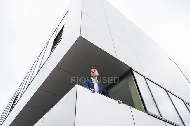 Jeune homme d'affaires debout sur le balcon d'un immeuble de bureaux — Photo de stock