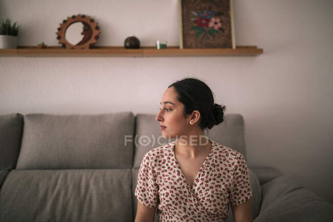 Giovane donna premurosa seduta sul divano a casa — Foto stock