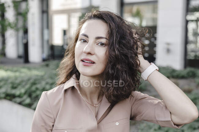 Fiduciosa donna d'affari con mano nei capelli fuori dall'edificio degli uffici — Foto stock