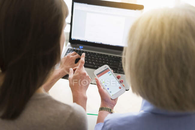 Rückansicht von Seniorin und erwachsener Tochter mit Laptop und Smartphone — Stockfoto