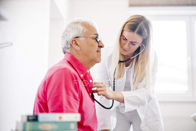 Médecin femme examinant une patiente âgée en clinique médicale — Photo de stock