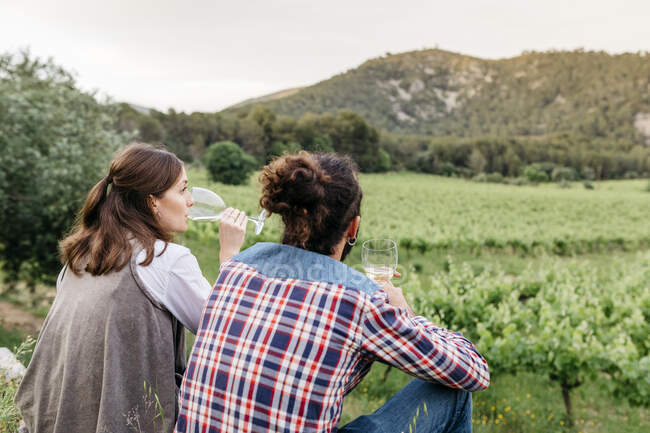 Couple tasting white wine while sitting at vineyard — Stock Photo