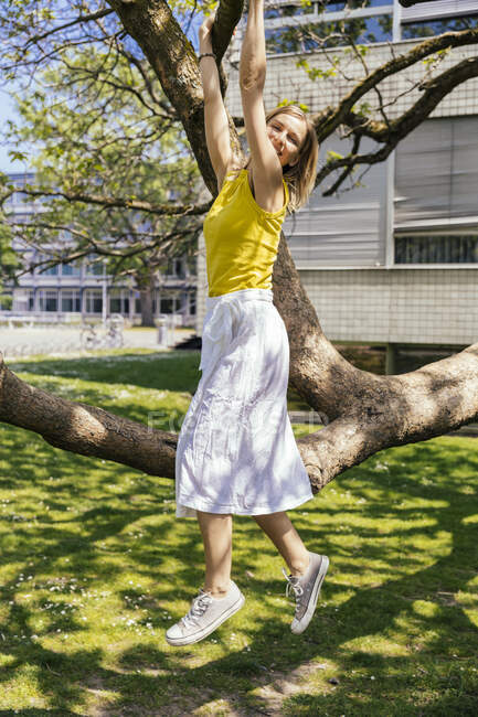 Ritratto di donna felice appesa a un ramo di un albero — Foto stock