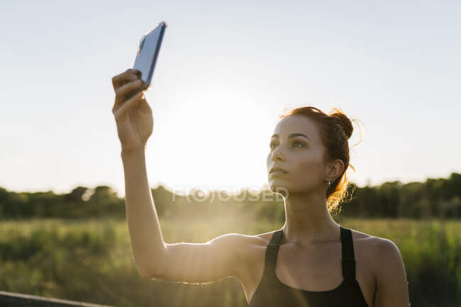 Giovane donna utilizzando il telefono contro il cielo limpido — Foto stock