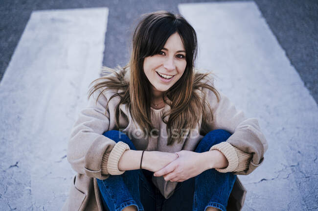 Портрет усміхненої молодої жінки, що сидить на перехресті зебри — стокове фото