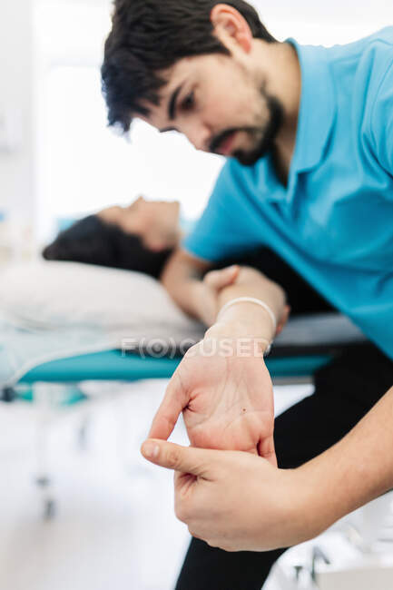 Terapista di sesso maschile ipovedente che cura la mano della donna in clinica — Foto stock