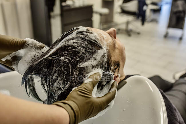 Mujer en peluquería lavándose el pelo con cepillos - foto de stock