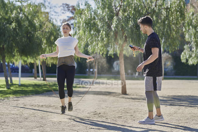 Donna durante l'allenamento con allenatore saltare la corda nel parco — Foto stock