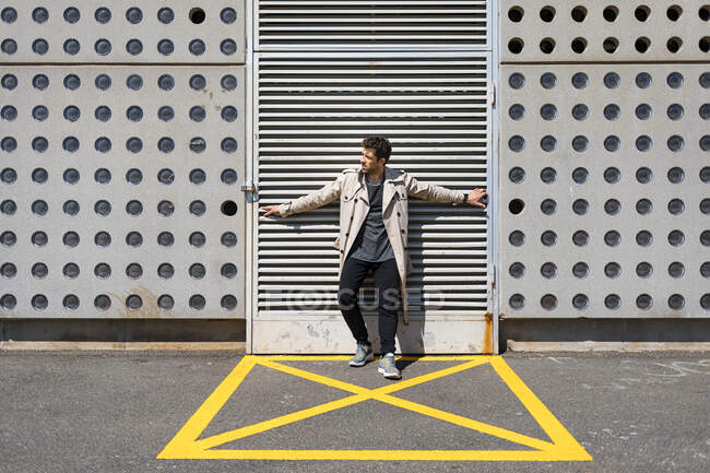 Homem adulto médio em pé na área amarela marcada na frente da parede de concreto, com os braços estendidos — Fotografia de Stock