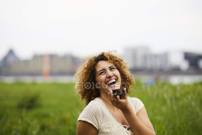 Портрет смеющейся женщины со смартфоном на улице — стоковое фото