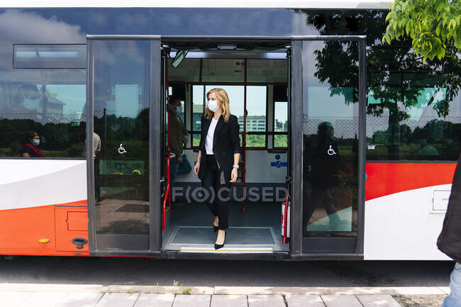 Доросла комерсантка в захисній масці виходить з громадського автобуса (Іспанія). — стокове фото