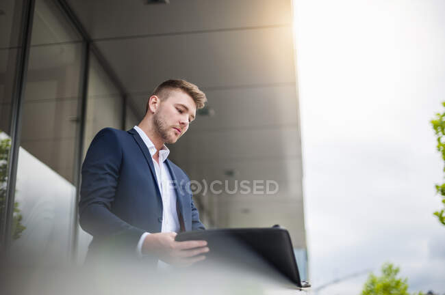 Portrait of a young businessman looking at folder in the city — Stock Photo
