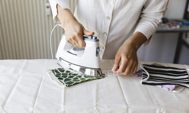 Woman ironing homemade mask on board — Stock Photo