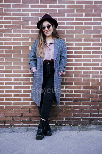 Portrait of fashionable woman standing in front of brick wall — Stock Photo
