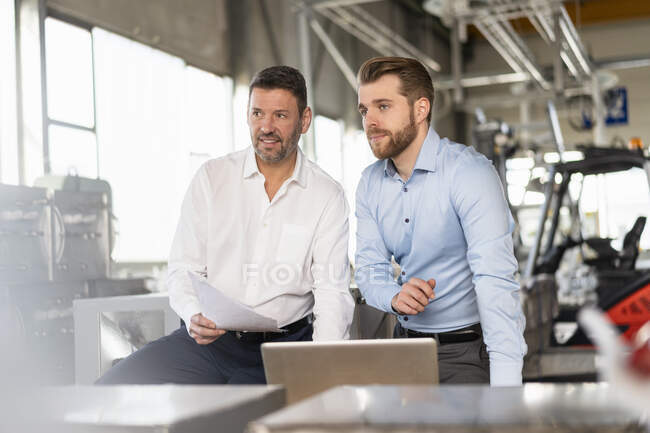 Два бизнесмена с ноутбуком встречаются на заводе — стоковое фото