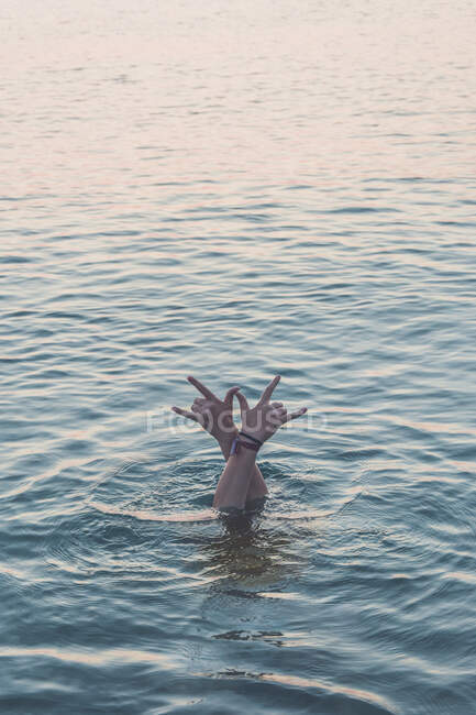 Руки девочки-подростка, ныряющей в море, показывают знак рок-н-ролла — стоковое фото